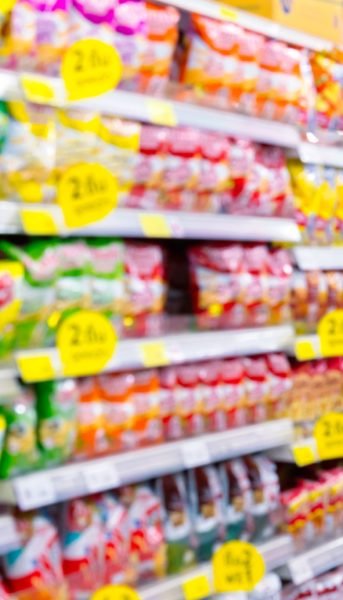 Blurred fast food snacks for sale on a supermarket shelf. A picture with grain and color from film simulation filter.